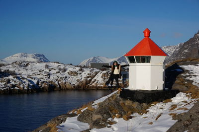 Full length of woman standing by lighthouse on snow covered mountain