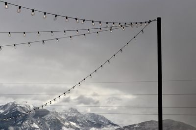 Low angle view of light bulbs hanging against sky