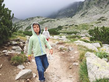 Siblings walking on mountain during foggy weather