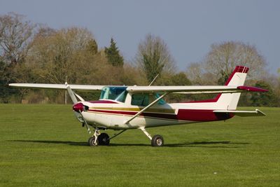 Side view of airplane on field against sky