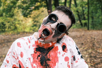 Close-up portrait of zombie face with traces of blood and black fluid coming out of the mouth. 