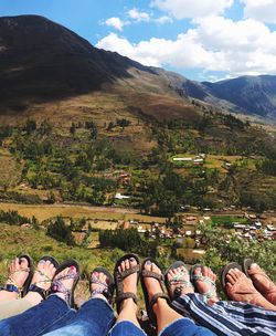 People relaxing on mountain against sky