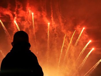 Silhouette person looking at firework display at night