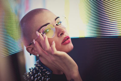 Portrait of young woman with shaved head standing against abstract backgrounds