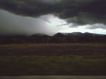 Scenic view of field against storm clouds