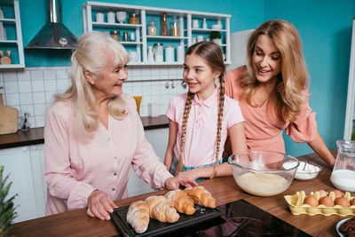 Cheerful daughter with parents preparing food at kitchen