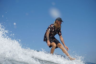 Full length of man surfing on sea against clear sky