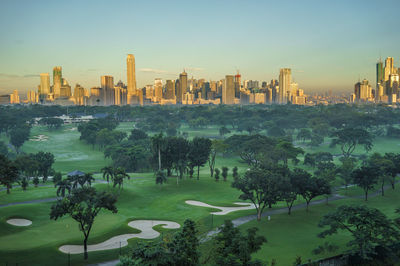 Golf course and city against sky