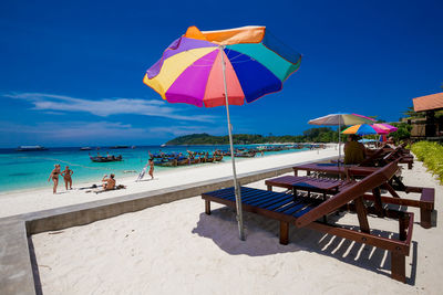 Deck chairs by swimming pool at beach against sky