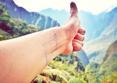 Close-up of woman hand against mountain range