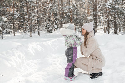 Mother and daughter play in the snowy forest on a weekend. high quality photo