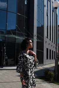 Full length of woman standing on footpath against building in city