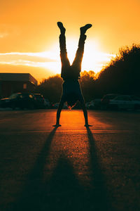 Silhouette man doing handstand during sunset