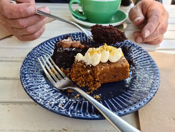 Midsection of person with cake and cream in plate