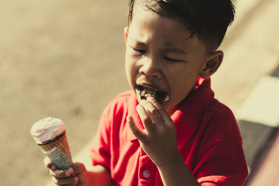 Close-up of boy holding ice cream outdoors
