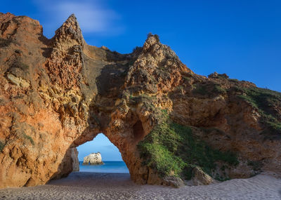 Rock formations by sea against blue sky