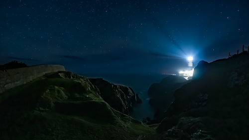 Scenic view of rocks at sea against sky at night