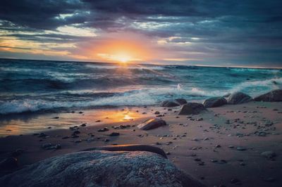 Scenic view of sea against dramatic sky during sunset