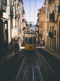 Railroad tracks by street in city against sky