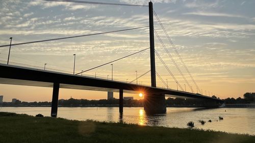 Bridge over river against sky during sunset