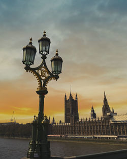 Street light by building against sky during sunset