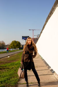 Portrait of young woman standing against clear sky