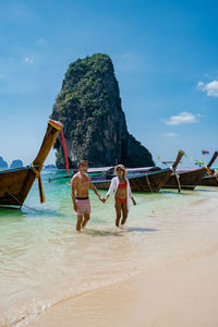 Rear view of women on beach against sky