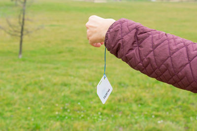 Cropped hand of woman holding label outdoors