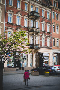 Rear view of woman walking on street against building