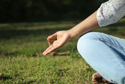 Midsection of woman doing yoga on field