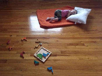 High angle view of baby lying on hardwood floor at home