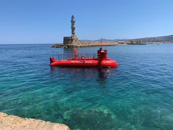 Red boat on sea against clear sky