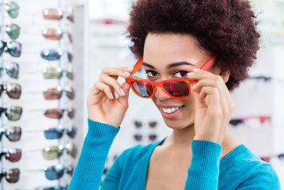 Portrait of young woman holding sunglasses