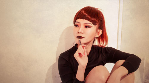 Portrait of young woman against wall