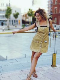 Full length of smiling young woman looking away while standing in city