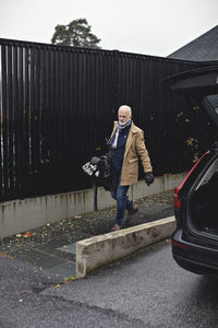 Senior man with golf bag walking on sidewalk during winter