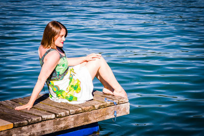 Woman sitting by sea