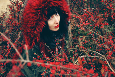 High angle portrait of woman wearing warm clothing amidst red berries on plants