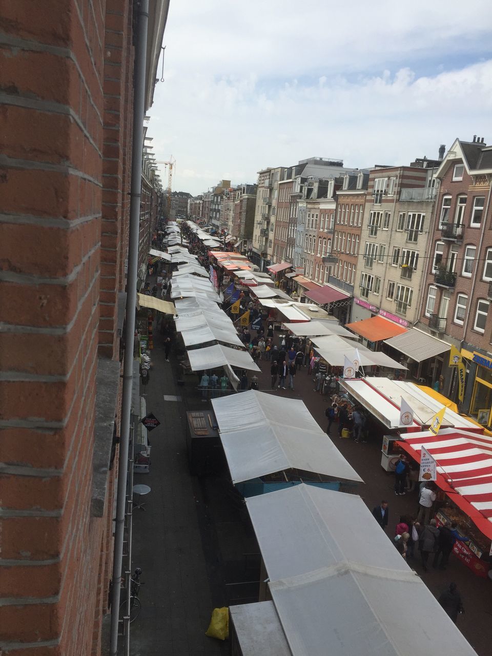 architecture, building exterior, built structure, sky, city, street, transportation, the way forward, road, cloud - sky, building, day, residential structure, outdoors, diminishing perspective, residential building, city life, vanishing point, incidental people, wall - building feature