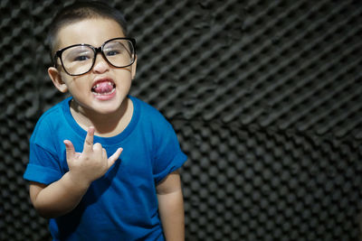 Portrait of boy sticking out tongue while gesturing horn sign