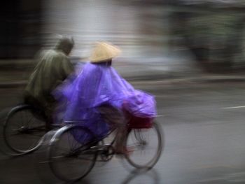 Blurred motion of people riding bicycle on road