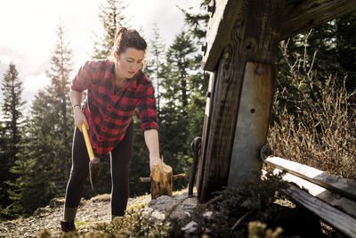 Woman cutting wood with axe on field