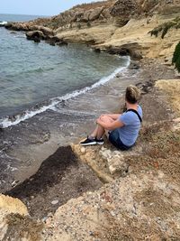 Woman sitting on rock at beach