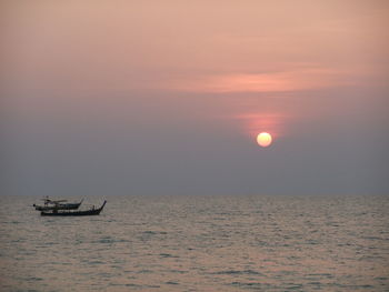 Sailboat in sea against sky during sunset