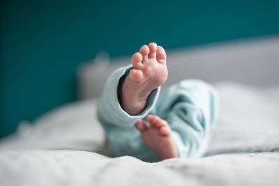 Low section of baby lying on bed