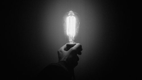 Close-up of hand holding illuminated light against black background