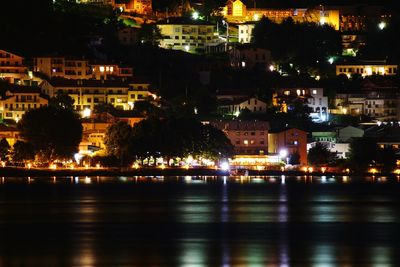 Illuminated cityscape by river at night