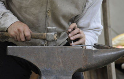 Midsection of man working on metal in workshop