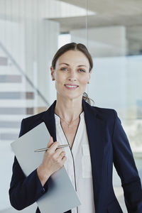 Smiling businesswoman standing with clipboard