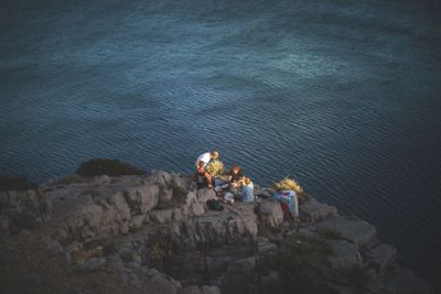 High angle view of people standing on rock by sea
